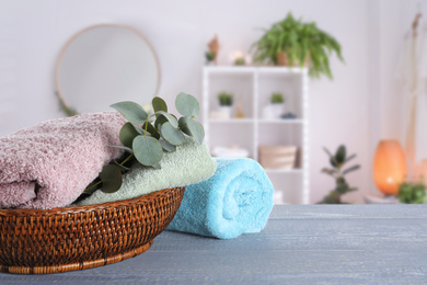 Image of Fresh towels and eucalyptus branches on grey wooden table in bathroom. Space for text