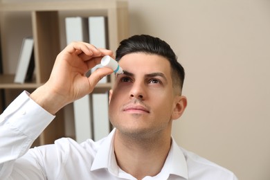 Photo of Man using eye drops in light office
