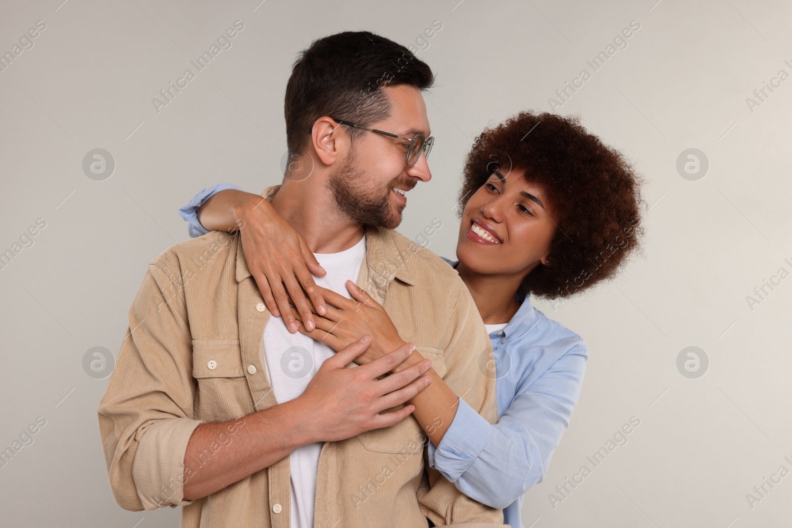 Photo of International dating. Happy couple hugging on light grey background