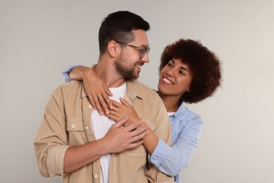 International dating. Happy couple hugging on light grey background