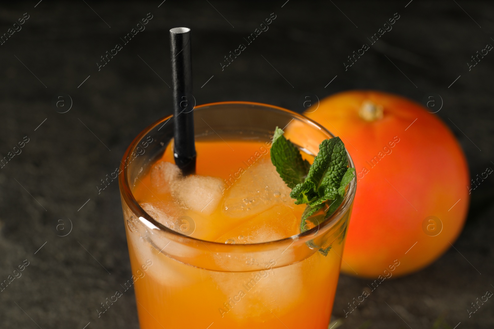Photo of Tasty grapefruit drink with ice and mint in glass on dark table, closeup