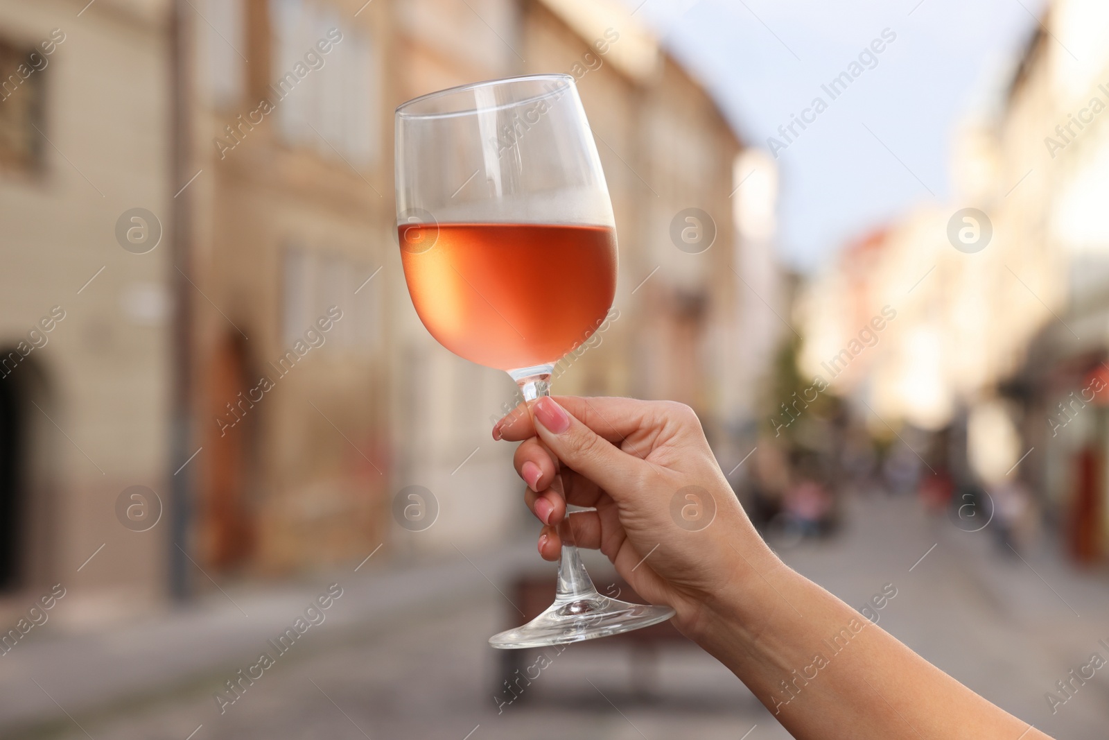 Photo of Woman holding glass of rose wine outdoors, closeup