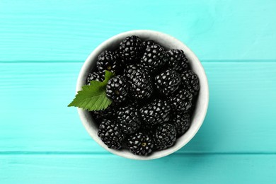 Photo of Bowl of fresh ripe blackberries on turquoise wooden table, top view