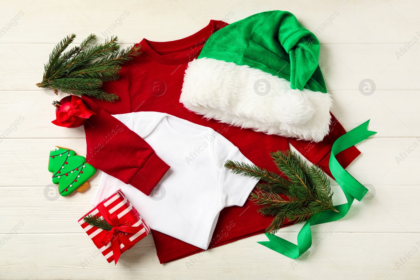 Photo of Flat lay composition with cute Christmas baby clothes on white wooden background