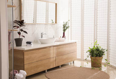 Photo of Stylish bathroom interior with countertop, mirror and plants. Design idea