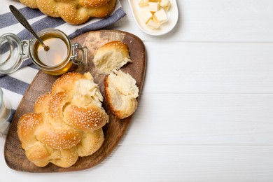 Homemade braided bread, butter and honey on white wooden table, flat lay with space for text. Traditional challah