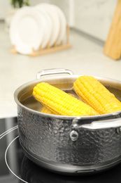 Pot with boiling corn on induction cooktop