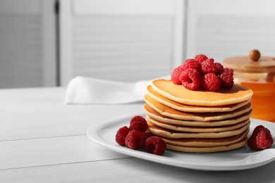 Photo of Stack of tasty pancakes with raspberries on white wooden table, space for text