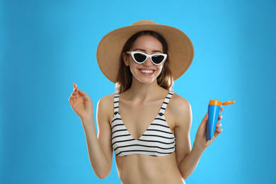 Photo of Young woman with sun protection cream on light blue background