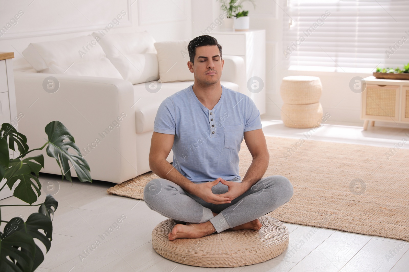 Photo of Man meditating on wicker mat at home