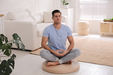 Man meditating on wicker mat at home
