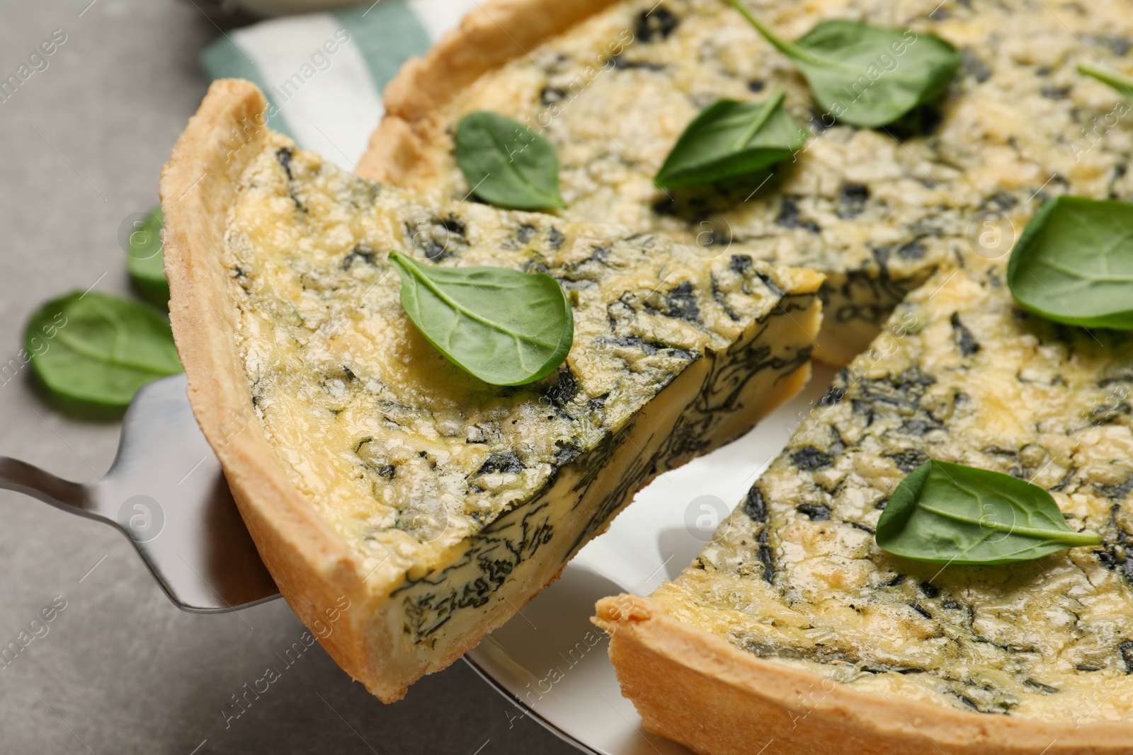 Photo of Delicious homemade spinach pie and spatula on grey table, closeup