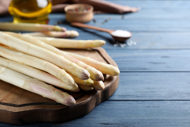 Photo of Fresh white asparagus on blue wooden table, closeup. Space for text