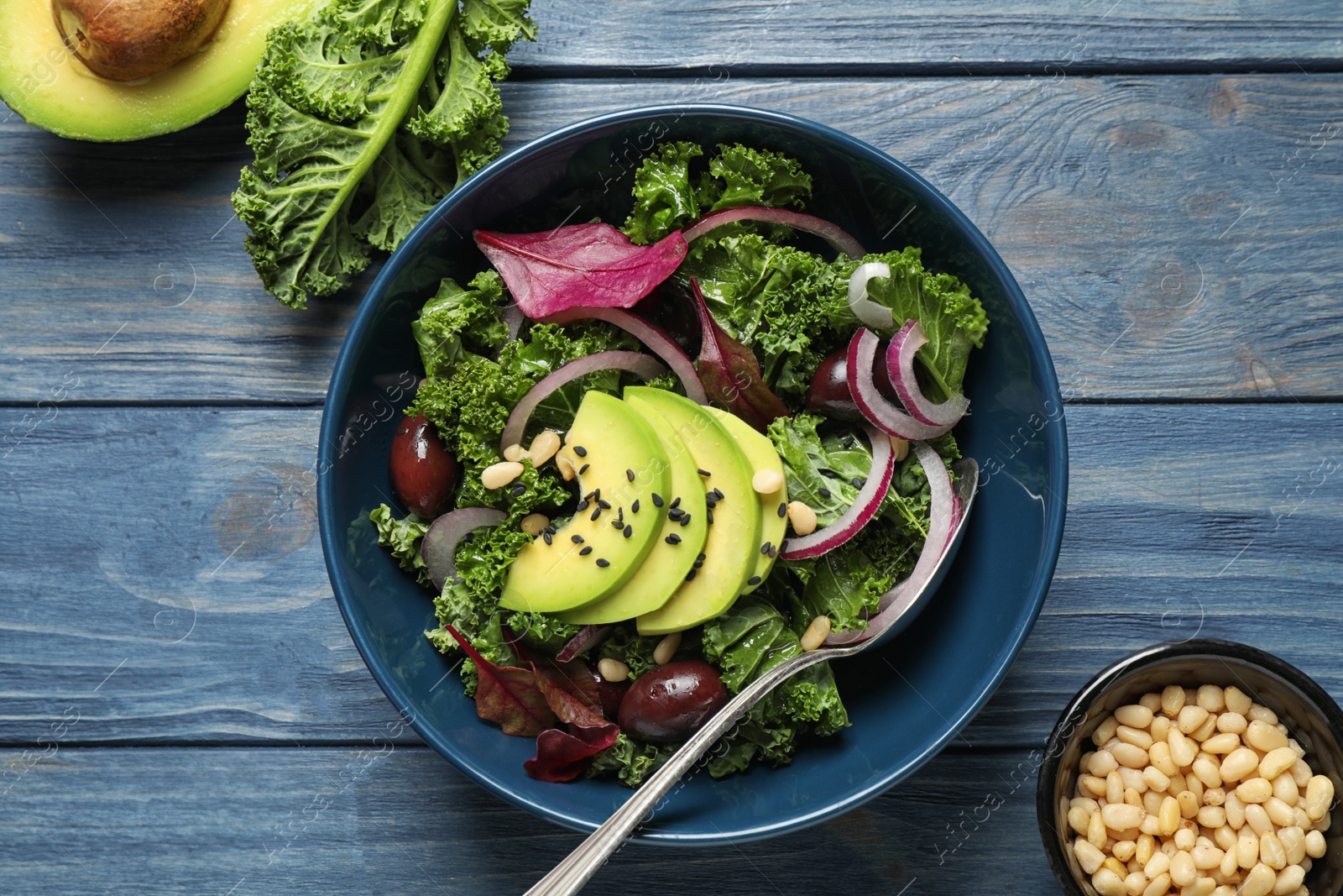 Photo of Tasty fresh kale salad on blue wooden table, flat lay