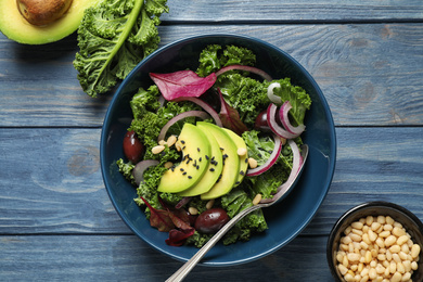 Photo of Tasty fresh kale salad on blue wooden table, flat lay