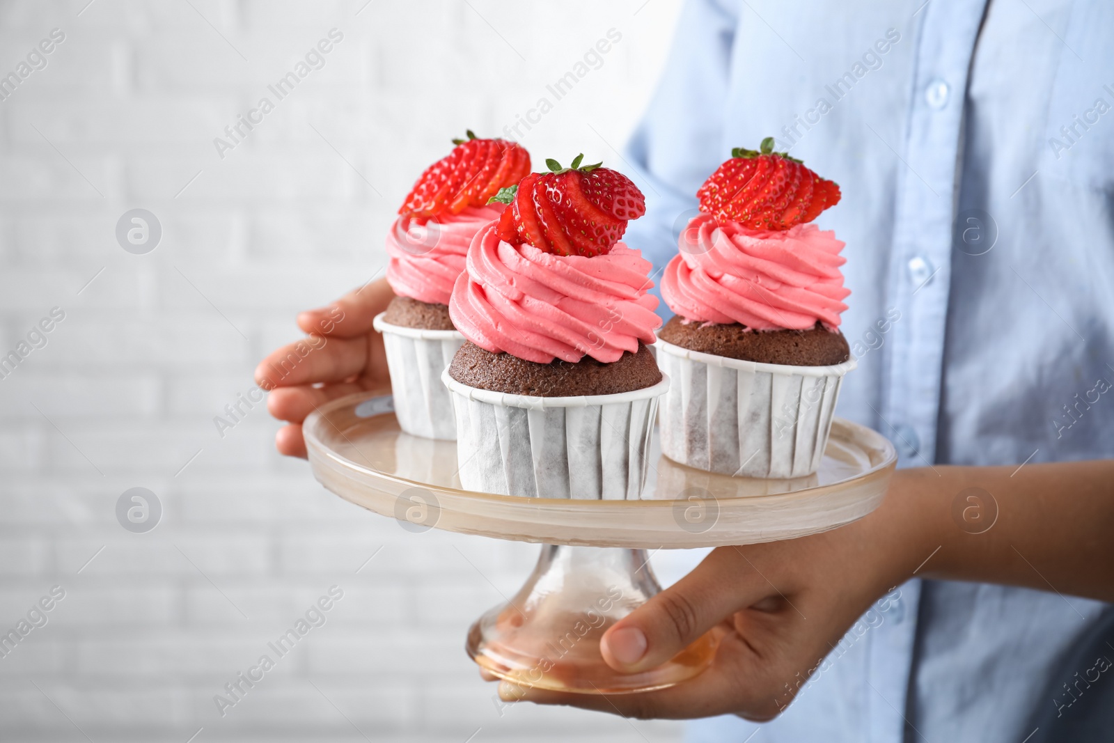 Photo of Woman holding dessert stand with sweet cupcakes, closeup