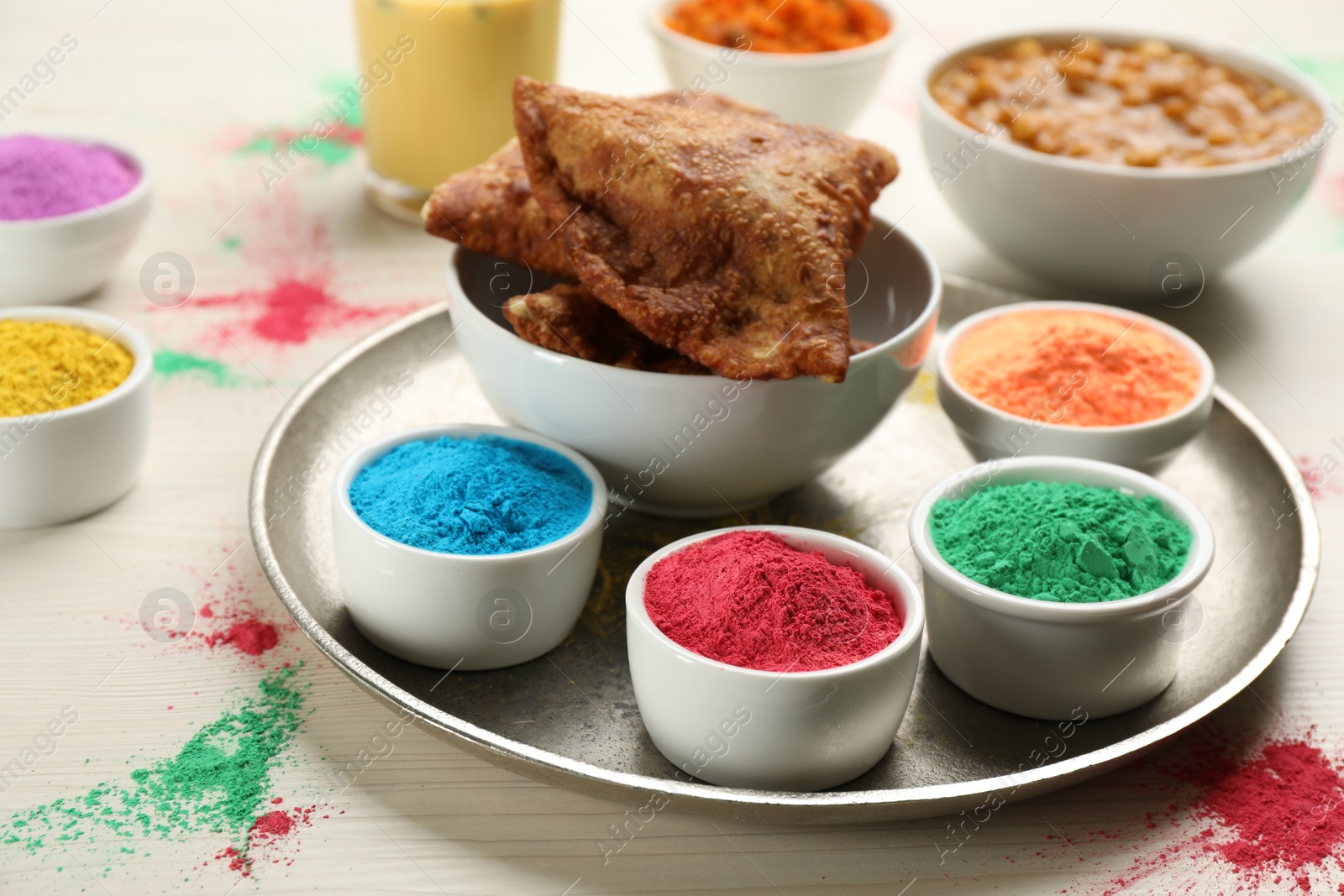 Photo of Traditional Indian food and color powders on white wooden table, closeup. Holi festival celebration