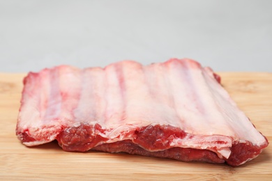 Photo of Board with raw ribs on grey background, closeup. Fresh meat