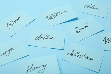Photo of Choosing baby name. Paper stickers with different names on light blue background