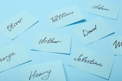 Choosing baby name. Paper stickers with different names on light blue background