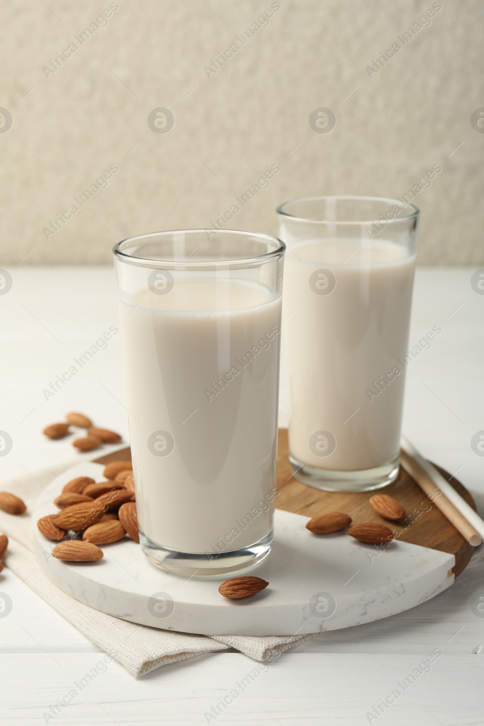 Photo of Glasses of almond milk and almonds on white wooden table