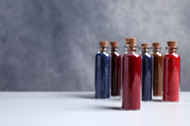 Photo of Glass bottles with different food coloring on white marble table. Space for text