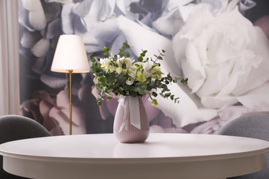 Photo of Vase with beautiful bouquet on white table indoors. Stylish interior element