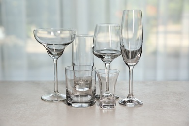 Photo of Different elegant empty glasses on grey table indoors