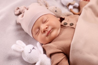 Photo of Cute newborn baby sleeping with toys on blanket, closeup