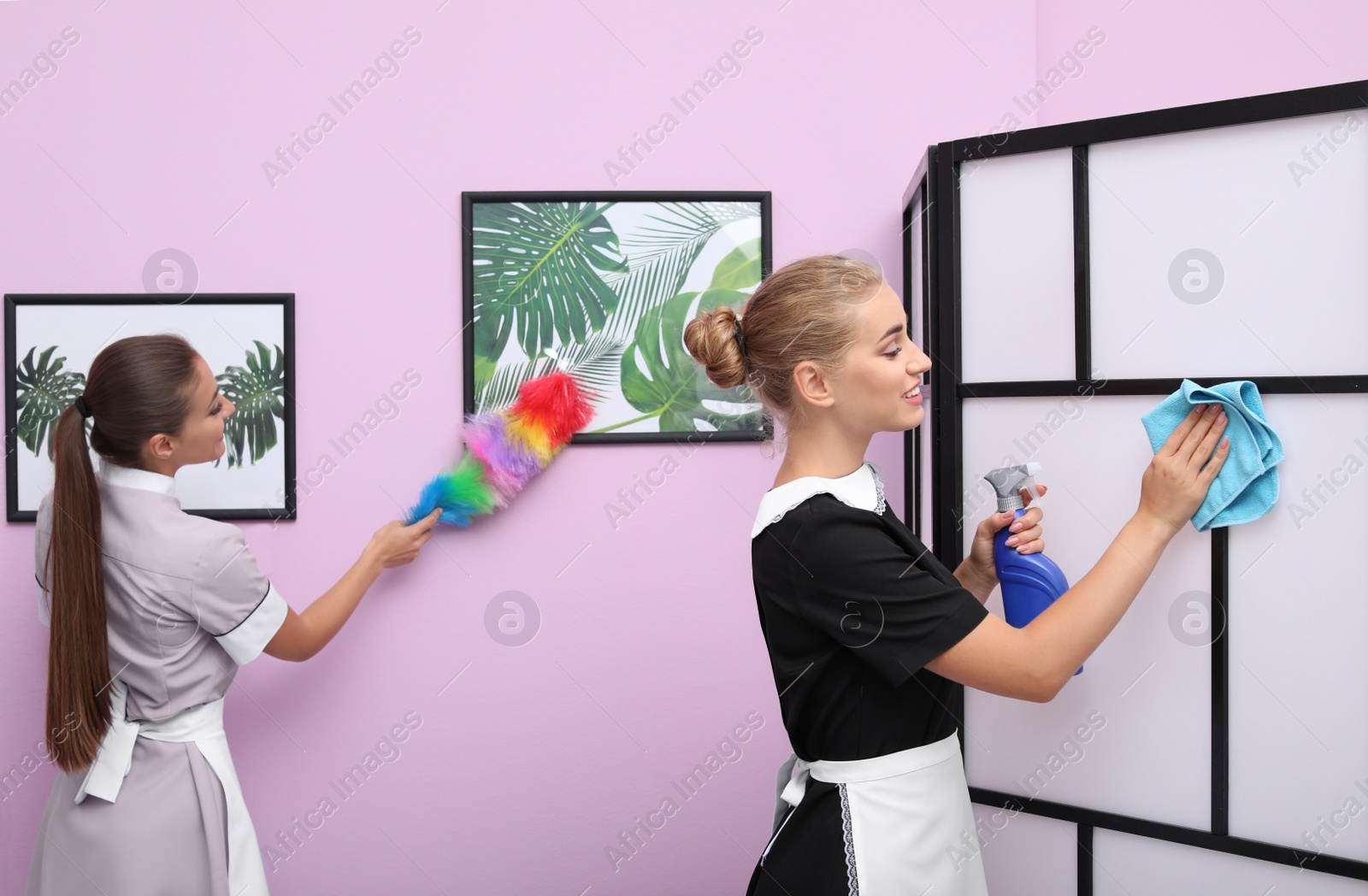 Photo of Professional chambermaids cleaning room in modern apartment