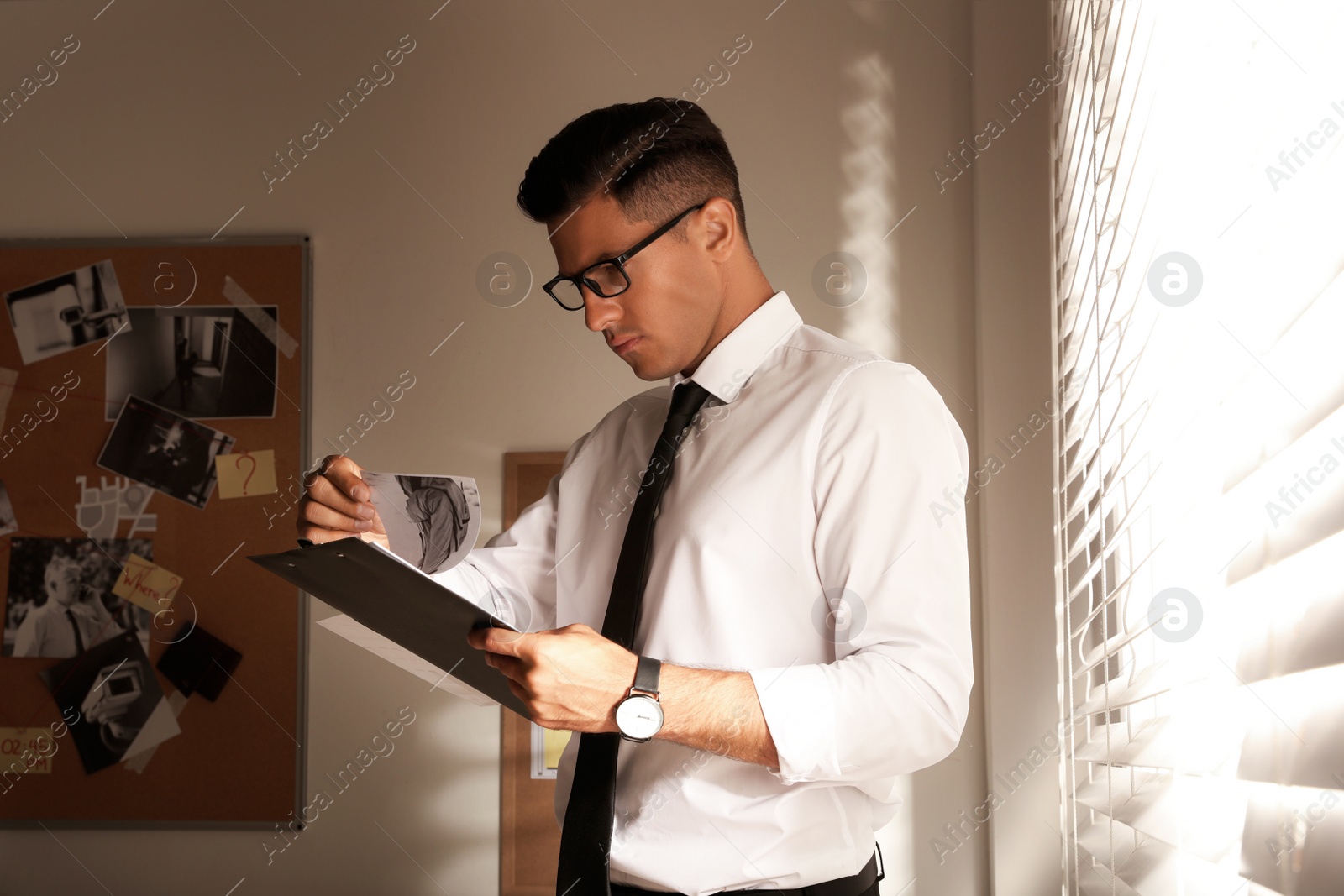 Photo of Detective with clipboard working in his office