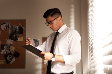 Photo of Detective with clipboard working in his office
