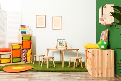 Stylish playroom interior with table and stools