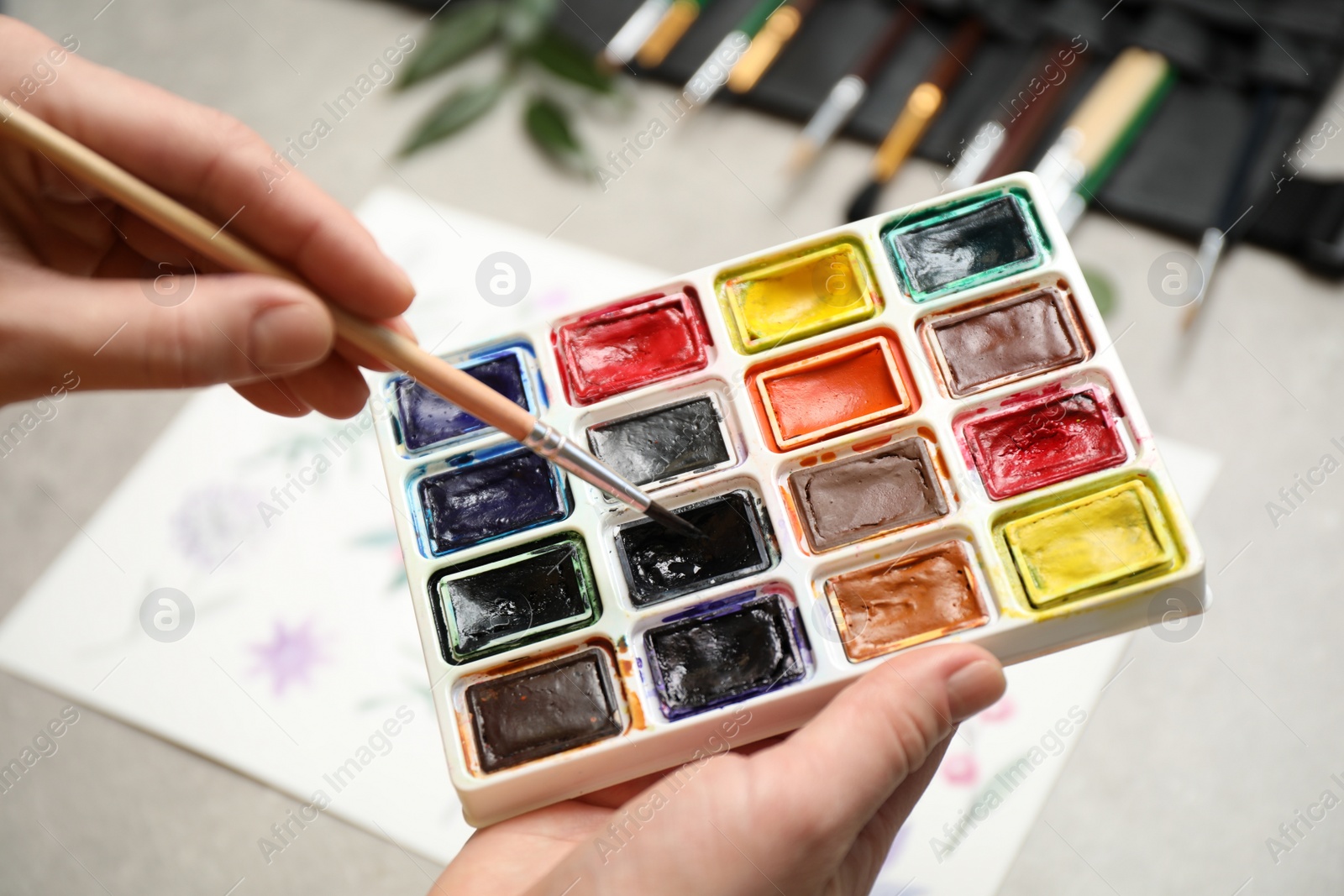 Photo of Woman holding brush and watercolor palette, closeup