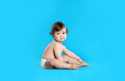 Photo of Cute little baby in diaper on light blue background. Space for text
