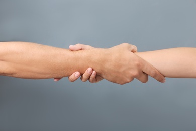 Photo of People holding hands together on gray background, closeup. Concept of support and help