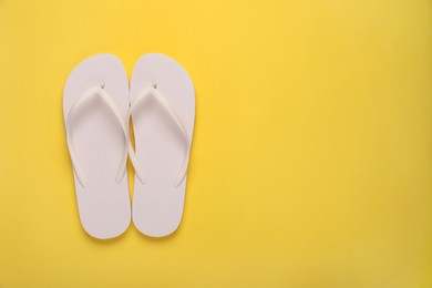 Stylish flip flops on yellow background, top view. Space for text