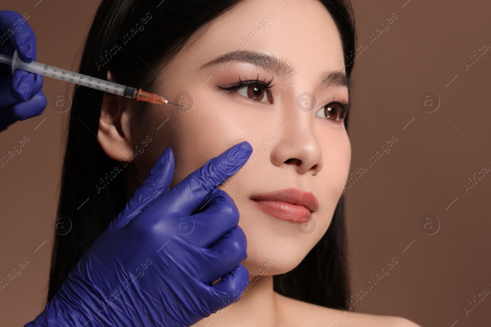 Photo of Woman getting facial injection on brown background, closeup