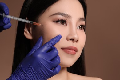 Woman getting facial injection on brown background, closeup