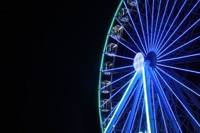 Photo of Beautiful glowing Ferris wheel against dark sky. Space for text