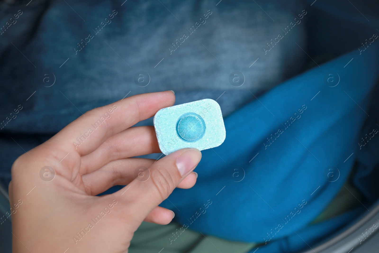 Photo of Woman putting water softener tablet into washing machine, closeup