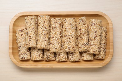 Plate with tasty sesame seed bars on wooden table, top view. Space for text