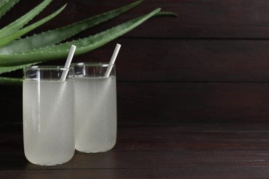 Photo of Tasty aloe juice in glasses on wooden table, space for text