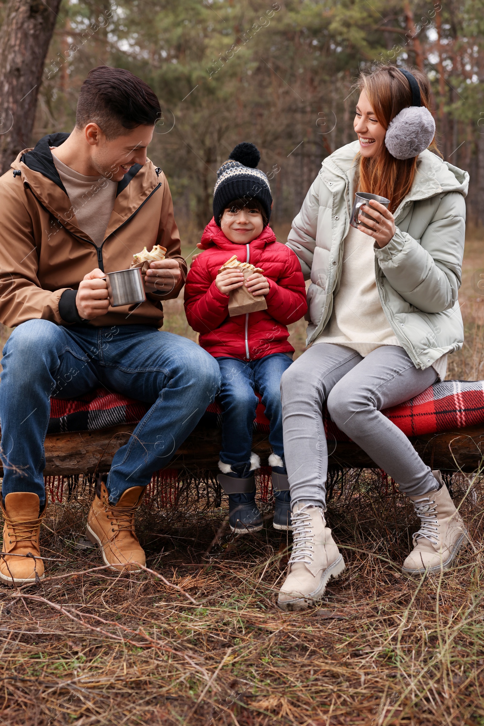 Photo of Happy family with sandwiches and hot drinks spending time together in forest
