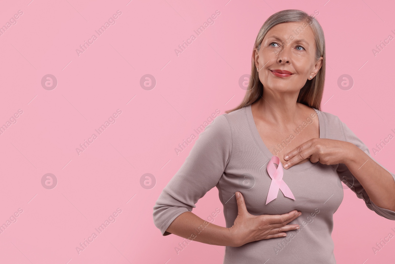 Photo of Beautiful senior woman with pink ribbon on color background, space for text. Breast cancer awareness