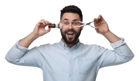 Handsome young man with mustache holding scissors and shaving brush on white background