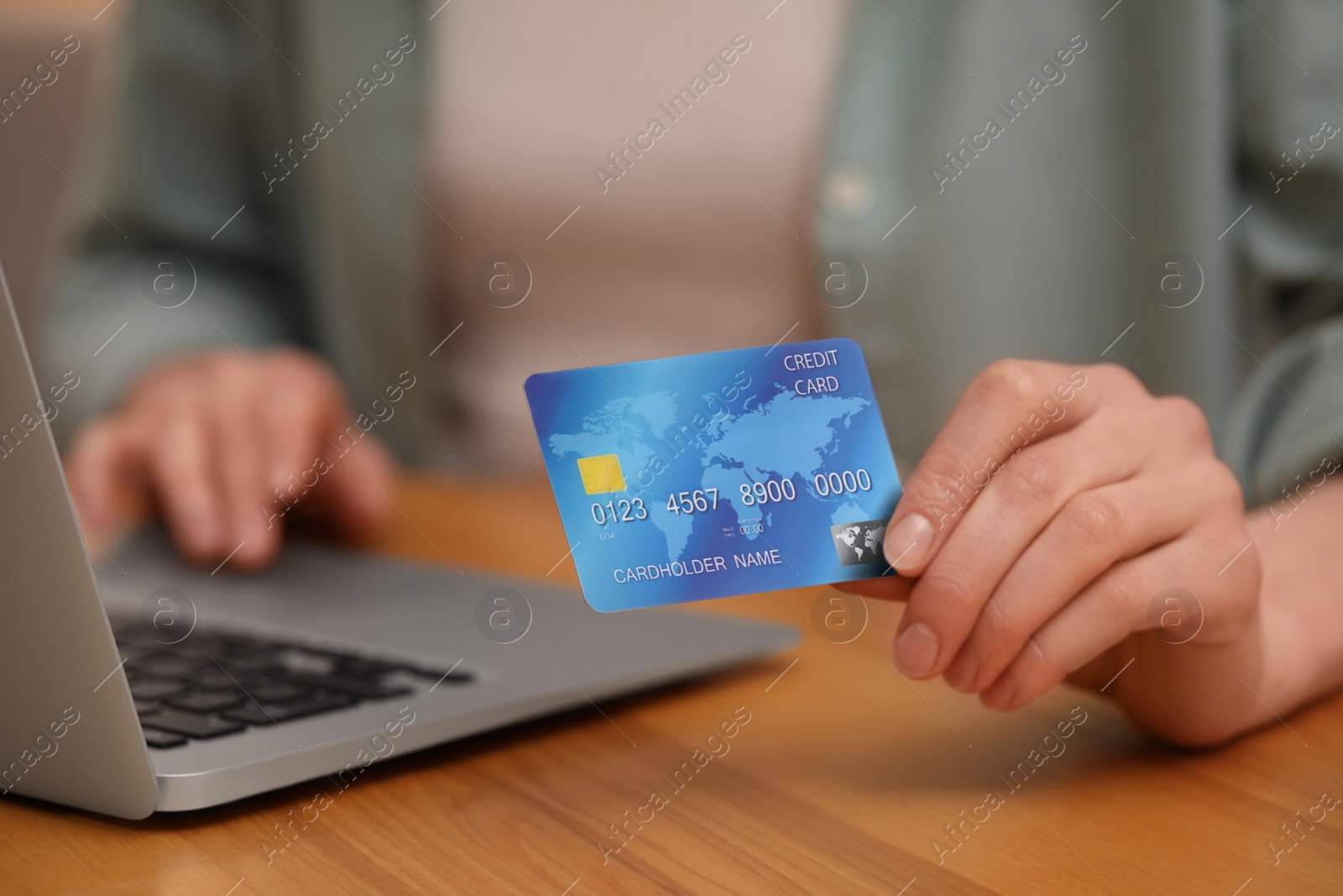 Photo of Woman with credit card using laptop for online shopping at wooden table, closeup