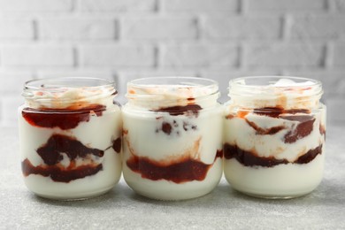 Photo of Tasty yoghurt with jam on grey table, closeup