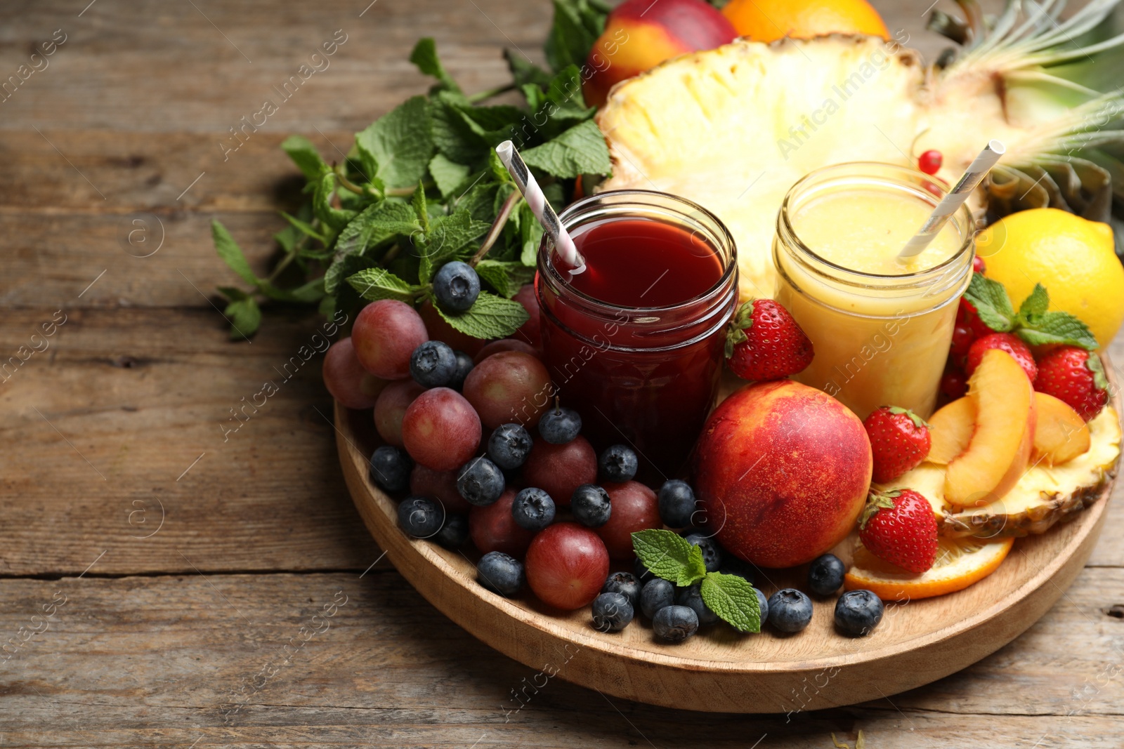 Photo of Delicious colorful juices in glasses and fresh ingredients on wooden table