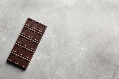 Photo of Chocolate bar on grey background, top view. Space for text